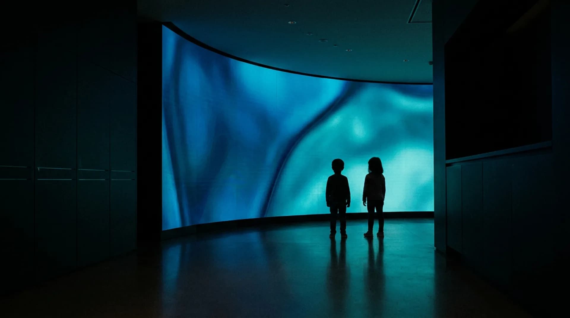 A curved LED wall tiling seamlessly around a corner in a dark lobby